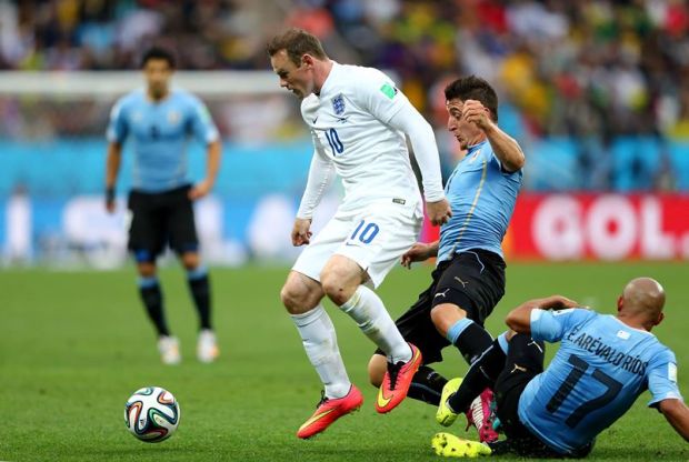 2014 FIFA World Cup - England's Wayne Rooney holds off challenges from Uruguay's Cristian Rodriguez and Edigio Arevalo.